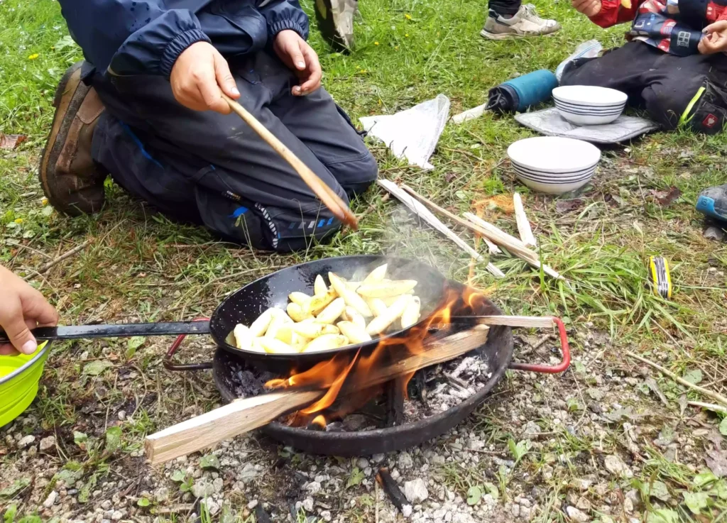 Kinder kochen am Feuer