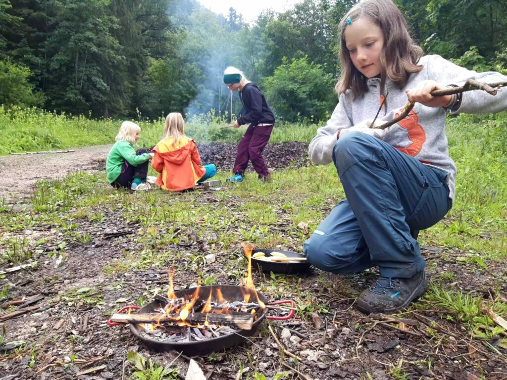 Kinder kochen am Feuer